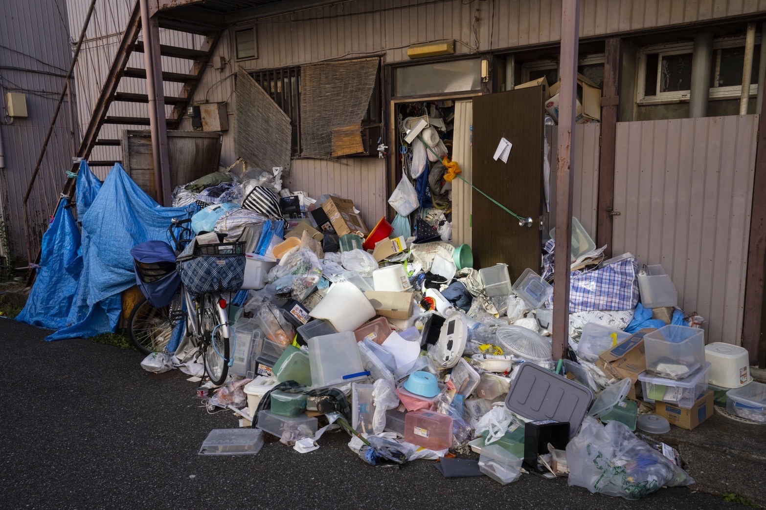 玄関から溢れ出した大量の生活ゴミと不用品